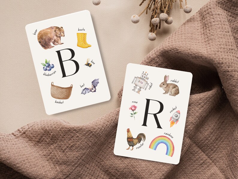 May include: Two white cards with colorful illustrations and the letters B and R. The B card shows a bear, boots, blueberries, a bee, a basket, and a bat. The R card shows a robot, a rabbit, a rose, a rocket, a rooster, and a rainbow.