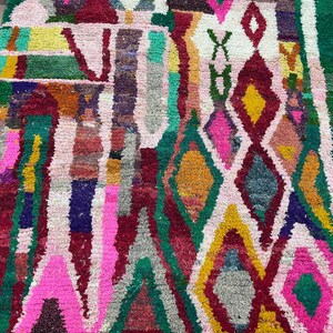 May include: A colorful Moroccan rug with a geometric pattern in shades of pink, green, yellow, and red.