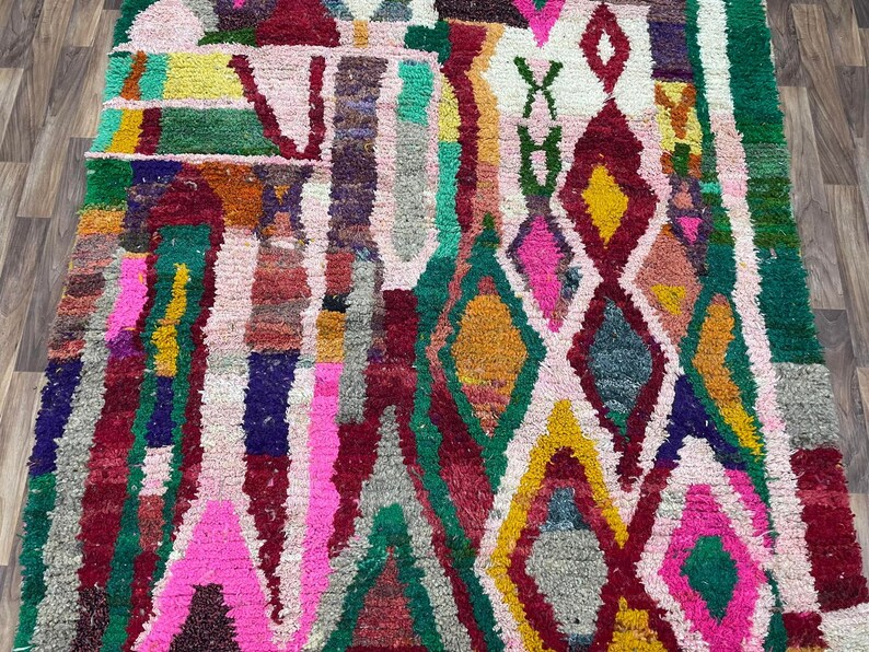 May include: A colorful Moroccan rug with a geometric pattern in shades of pink, green, yellow, and red.