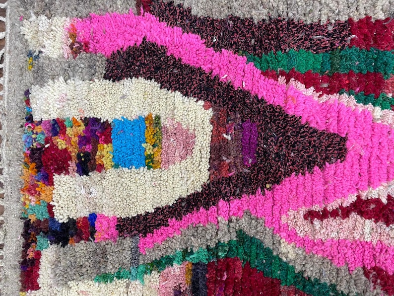 May include: A colorful Moroccan rug with a pink, green, and red geometric pattern. The rug is made of wool and has a soft, fluffy texture.