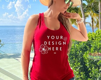 May include: A red vest top with the text "YOUR DESIGN HERE" and a floral graphic. The top is worn with denim shorts. The image is taken outdoors with a tropical backdrop.