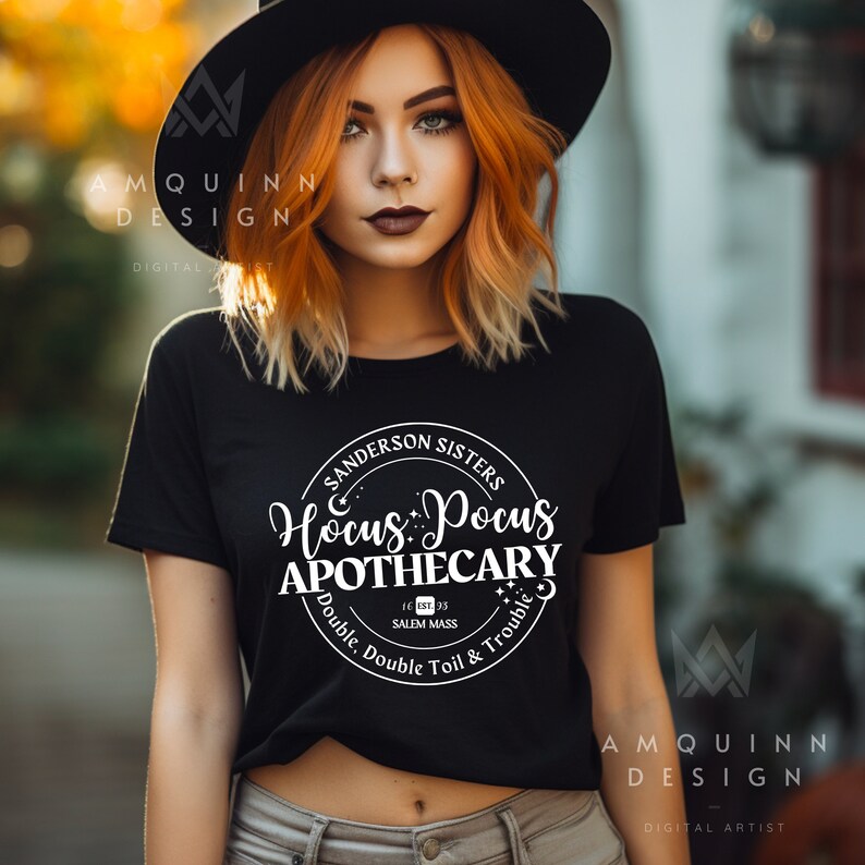 May include: Black t-shirt with a white graphic that reads "Sanderson Sisters Hocus Pocus Apothecary" in a circular design. The text includes "Double, Double Toil & Trouble" and "Salem Mass". The shirt is a crew neck.