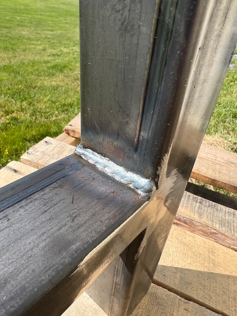 Puede incluir: Primer plano de una uni&oacute;n de metal soldada, que muestra una construcci&oacute;n s&oacute;lida y robusta. El metal es de color gris oscuro y la soldadura es de color gris claro. La soldadura es lisa y uniforme, lo que indica una construcci&oacute;n de alta calidad.