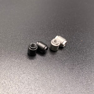 May include: Three metal connector pieces, two black and one silver, on a dark gray surface.