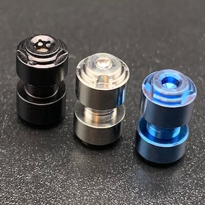 May include: Three metal knobs in black, silver, and blue. Each knob has a unique design and is made of a different metal.