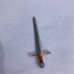 May include: A silver sword with a copper hilt and a red and yellow wrapped handle.