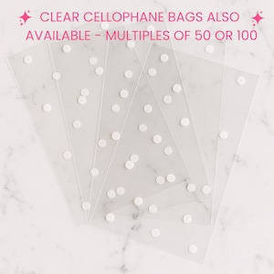 Peut inclure: Un ensemble de sacs en cellophane transparents rectangulaires avec un motif &agrave; pois blancs dispers&eacute;s. Le texte en haut indique : CLEAR CELLOPHANE BAGS ALSO AVAILABLE - MULTIPLES OF 50 OR 100. Les sacs sont dispos&eacute;s en &eacute;ventail sur un fond blanc.