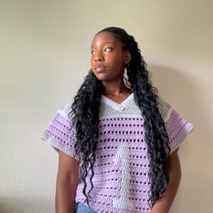 Puede incluir: Una camiseta de crochet de manga corta en lavanda, gris y blanco. La camiseta presenta un cuello en V y un dise&ntilde;o a rayas. El tejido abierto del crochet crea una prenda transpirable y elegante.