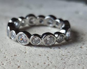 Elegante anillo de eternidad con bisel de plata y banda de circonita brillante.