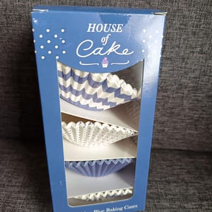 May include: A blue box of cupcake cases with the text "HOUSE of Cake". The box has a window showing three different styles of blue and white baking cups. The box reads "100 China Blue Baking Cases".