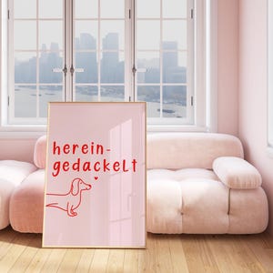 May include: A pink framed poster with a red dachshund illustration and the text "herein-gedackelt" on a pink background.