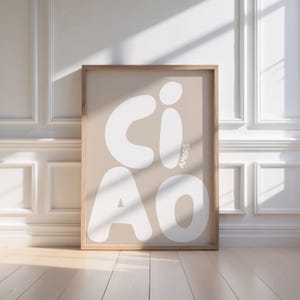K&ouml;nnte beinhalten: Ein gerahmter Kunstdruck mit dem Wort "CIAO" in gro&szlig;en, wei&szlig;en, abgerundeten Buchstaben auf beigem Hintergrund. Das Wort "AMORE" ist vertikal in Wei&szlig; gedruckt. Der Rahmen besteht aus hellbraunem Holz.