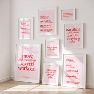 Op de afbeelding: Een verzameling ingelijste kunstprints met inspirerende citaten in rode tekst op een lichtroze achtergrond. De prints variëren in grootte en bevatten zinnen als "move like everything is gonna workout" en "universe, show me how good it gets."