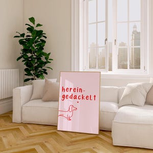 May include: A pink poster with a red dachshund illustration and the text "herein-gedackelt" in red.