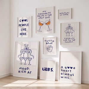 May include: A collection of framed art prints with white backgrounds and blue text. The prints feature phrases like "Cool People Live Here," "My Favourite Drink is the Next One," and "Living My Life to the Fullest." Some prints include illustrations of champagne glasses.