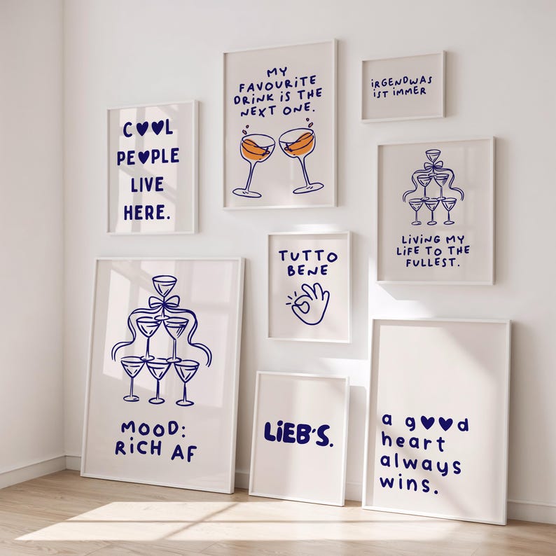 May include: A collection of framed art prints with white backgrounds and blue text. The prints feature phrases like "Cool People Live Here," "My Favourite Drink is the Next One," and "Living My Life to the Fullest." Some prints include illustrations of champagne glasses.