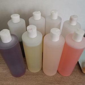 Peut inclure: Huit bouteilles en plastique transparentes avec des bouchons blancs, remplies de liquides de différentes couleurs. Les liquides sont violets, jaunes, roses et oranges.