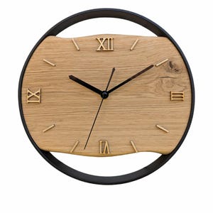May include: A round wooden wall clock with Roman numeral markings and black hands. The clock face is made of light brown wood with a dark brown wood grain pattern. The clock is surrounded by a black metal frame.