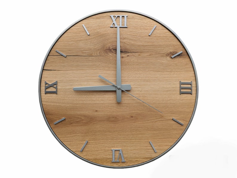 May include: A round wooden clock with Roman numeral markings and silver hands. The clock face is made of light brown wood with a natural grain pattern.