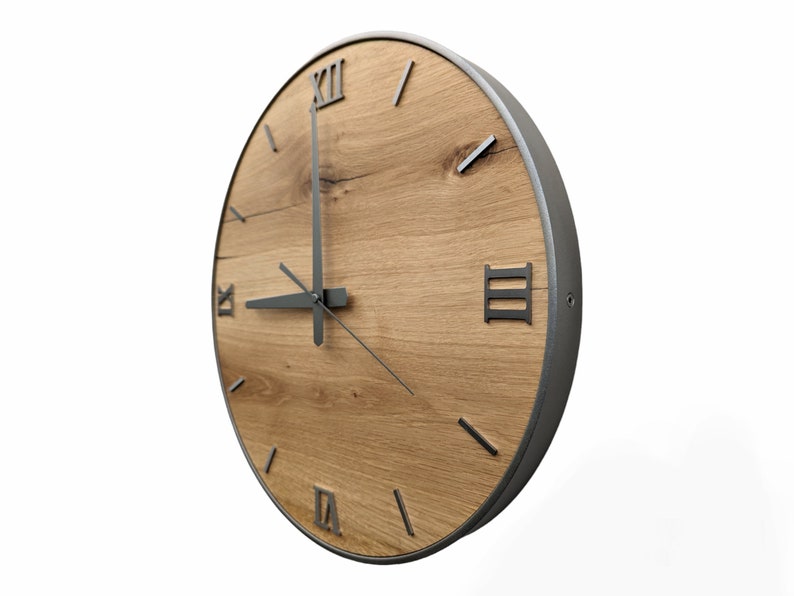 May include: A round wooden clock with Roman numeral markings and black metal hands. The clock face is made of light brown wood with a dark brown wood grain pattern. The clock has a silver metal frame.
