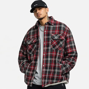 May include: A red, black, and white plaid flannel shirt jacket with two chest pockets and a button-up front. The jacket has a quilted lining and a black baseball cap.