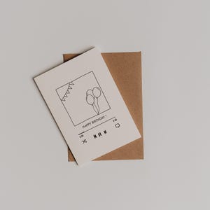 以下が含まれることがあります： 風船とバナーが描かれたビデオプレーヤーの画面の黒の線画が描かれた白いカード。カードのテキストは「Happy Birthday！」で、再生ボタンのアイコンがあります。