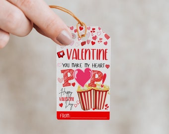May include: A white Valentine's Day gift tag with red hearts and the text "Valentine You Make My Heart POP!" with a drawing of two red and white striped popcorn containers. The tag also says "Happy Valentine Day" and "From:"