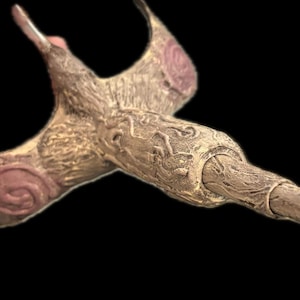 Könnte beinhalten: Ein Zauberstab aus Holz mit braunem und rosafarbenem Design und einem grünen Blatt am Ende.