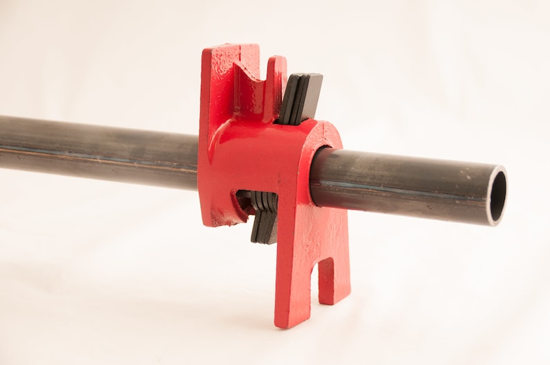May include: Red metal pipe clamp with black rubber pads. The clamp is attached to a black metal pipe.