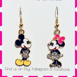 Puede incluir: Pendientes de aro dorados con Mickey y Minnie Mouse. Los pendientes tienen esmalte negro y blanco con pedrer&iacute;a y detalles rosas.
