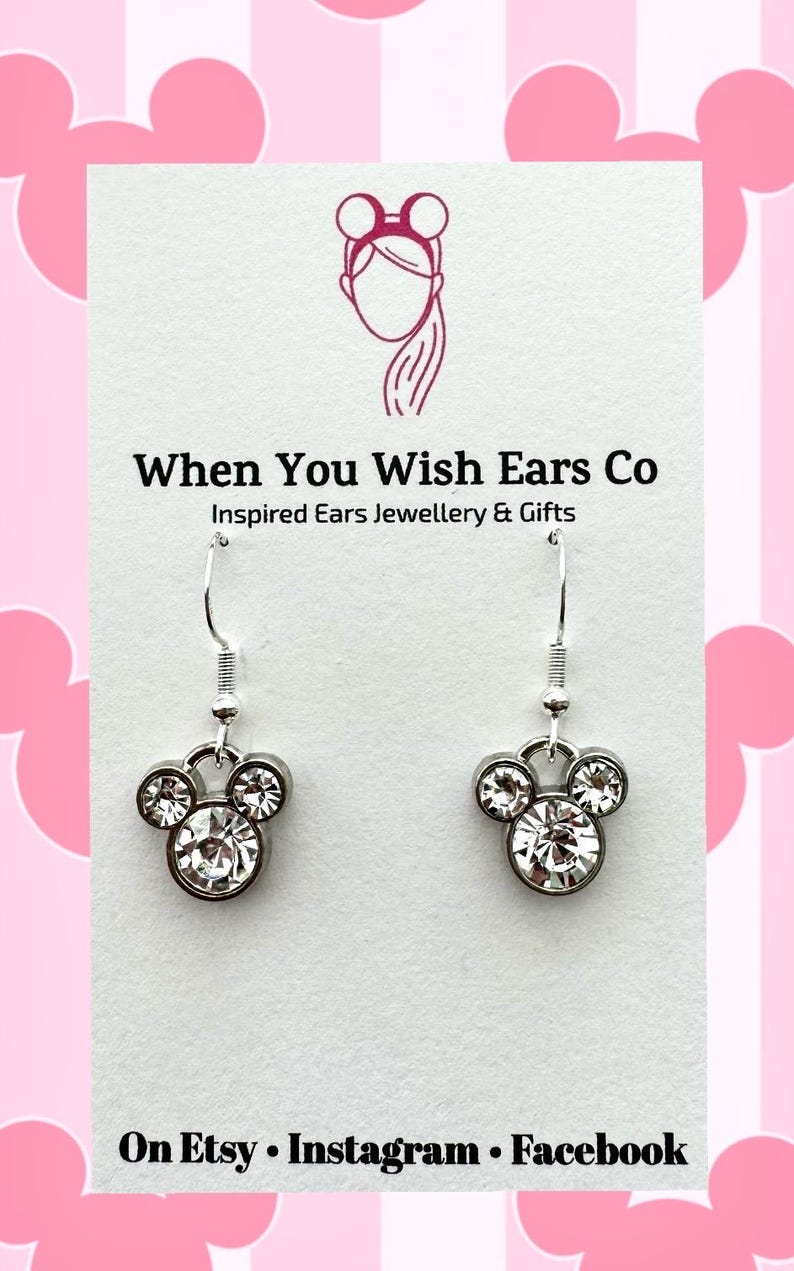 Puede incluir: Pendientes de plata con un dise&ntilde;o de cabeza de Mickey Mouse de cristal. Los pendientes est&aacute;n en una tarjeta blanca con el texto "When You Wish Ears Co. Inspired Ears Jewellery & Gifts. On Etsy Instagram Facebook."