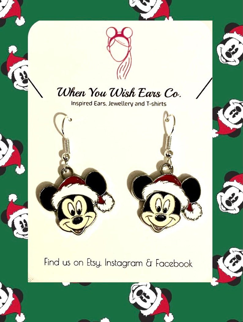 May include: Silver dangle earrings featuring a Mickey Mouse head wearing a Santa hat. The earrings are on a white background with the text "When You Wish Ears Co. Inspired Ears, Jewellery and T-shirts" and "Find us on Etsy. Instagram & Facebook".