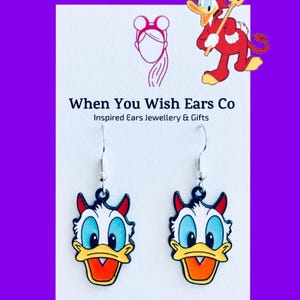 Op de afbeelding: Een paar hangende oorbellen met een cartoon eend met duivelshoorns. De eend heeft een gele snavel, blauwe ogen en een wit gezicht. De oorbellen zijn op een witte achtergrond met de tekst "When You Wish Ears Co. Inspired Ears Jewellery & Gifts" en "On Etsy - Instagram - Facebook".