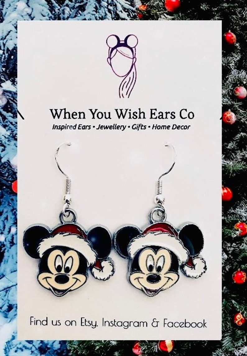 May include: A pair of silver dangle earrings featuring a cartoon Mickey Mouse wearing a Santa hat. The earrings are on a white background with the text "When You Wish Ears Co" and "Inspired Ears - Jewellery - Gifts - Home Decor".