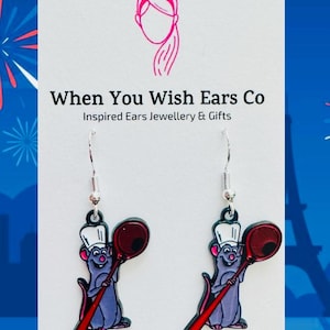 May include: A pair of silver dangle earrings featuring a cartoon chef rat holding a red spatula. The earrings are from When You Wish Ears Co. Inspired Ears Jewellery & Gifts. The text on the card reads "When You Wish Ears Co. Inspired Ears Jewellery & Gifts. On Etsy. Instagram. Facebook."