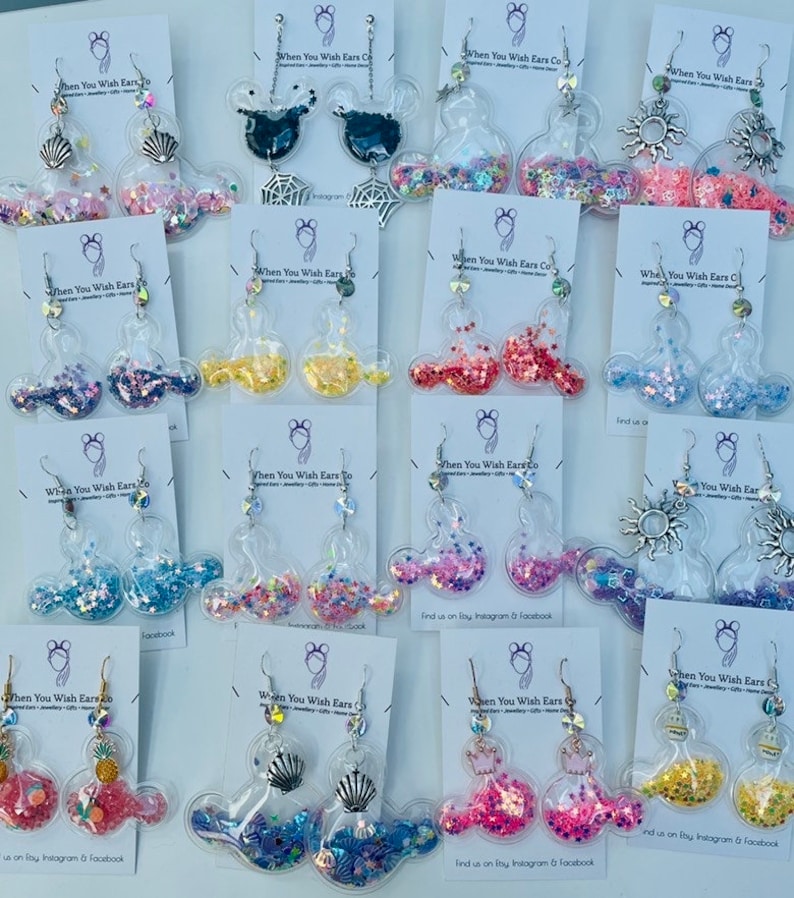May include: Assortment of colorful glitter filled Mickey Mouse ear earrings. The earrings are made of clear plastic and feature different glitter colors and designs.  Find us on Instagram & Facebook.