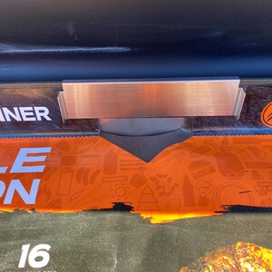 May include: A close-up of a metal food warmer with a brushed finish. The warmer is attached to a box with the word "DINNER" in white letters. The box has an orange and black design with the words "MIDDLE EDITION" in white letters.