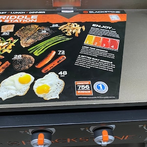 May include: Blackstone 36-inch griddle cooking station with a black and orange control panel. The griddle has a 756 square inch cooking surface and comes with a 1-year warranty. The image shows a variety of foods that can be cooked on the griddle, including bacon, eggs, hot dogs, asparagus, and steak.