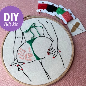 Könnte beinhalten: DIY-Komplett-Stickset. Das Design zeigt eine Strichzeichnung einer Figur in einem grünen Bikini-Höschen. Die Hände haben roten Nagellack. Enthält Stickgarn und Nadel.
