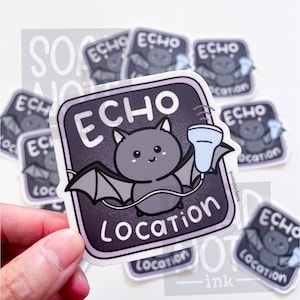 May include: A sticker featuring a cartoon bat with the words "ECHO LOCATION" in white. The bat is gray with outstretched wings and a smiling face. The sticker has a purple border and a light blue object in its hand.