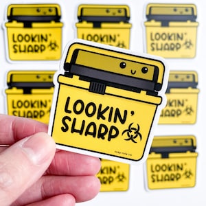 Puede incluir: Un conjunto de nueve pegatinas amarillas y negras con una imagen de dibujos animados de un contenedor de biohazard y el texto "Lookin' Sharp" con un símbolo de biohazard. Las pegatinas están sobre un fondo blanco.