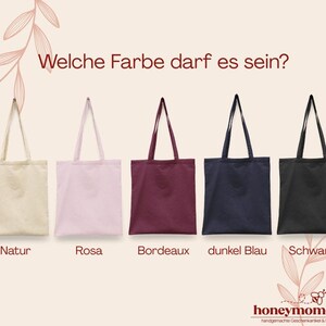 Peut inclure: Cinq sacs fourre-tout en tissu de diff&eacute;rentes couleurs : naturel, rose, bordeaux, bleu marine et noir. Le texte allemand "Welche Farbe darf es sein?" est en haut. Le bas contient le texte "honeymoments".
