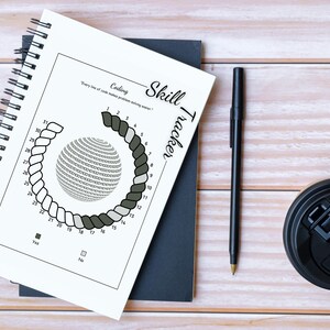 May include: A notebook with a coding skill tracker design. The notebook has a spiral binding and features a circular graphic with numbers and the text "Coding Skill Tracker." A black pen and a coffee cup are also on the wooden surface.