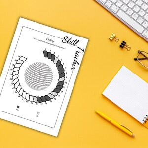 May include: A white paper with a coding skill tracker, a spiral design, and the text "Coding Skill Tracker". The paper is on a yellow surface with a keyboard, glasses, notepad, pen, and binder clips.