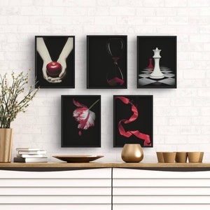 May include: Five black framed prints with different images. The images include a red apple, an hourglass, a white chess piece, a red ribbon, and a white tulip.