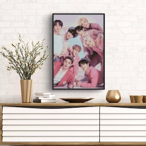 Può includere: Una foto incorniciata di un gruppo di otto uomini vestiti di rosa e bianco. Gli uomini sorridono e guardano la fotocamera. La foto è posizionata contro un muro di mattoni bianchi.