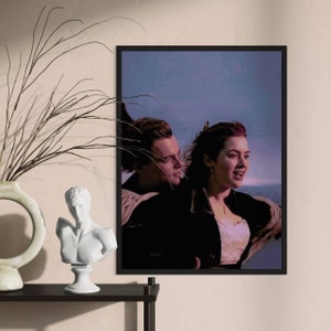 Puede incluir: Una impresión enmarcada de una escena romántica de la película Titanic. La imagen muestra a un hombre y una mujer de pie en la cubierta del barco, mirando hacia el océano. El hombre lleva una chaqueta oscura y la mujer lleva un vestido blanco. El fondo es un cielo azul y el océano.