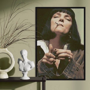 Può includere: Un poster incorniciato in bianco e nero con una donna dai capelli scuri e un'espressione seria. Tiene una sigaretta in mano e guarda direttamente lo spettatore.