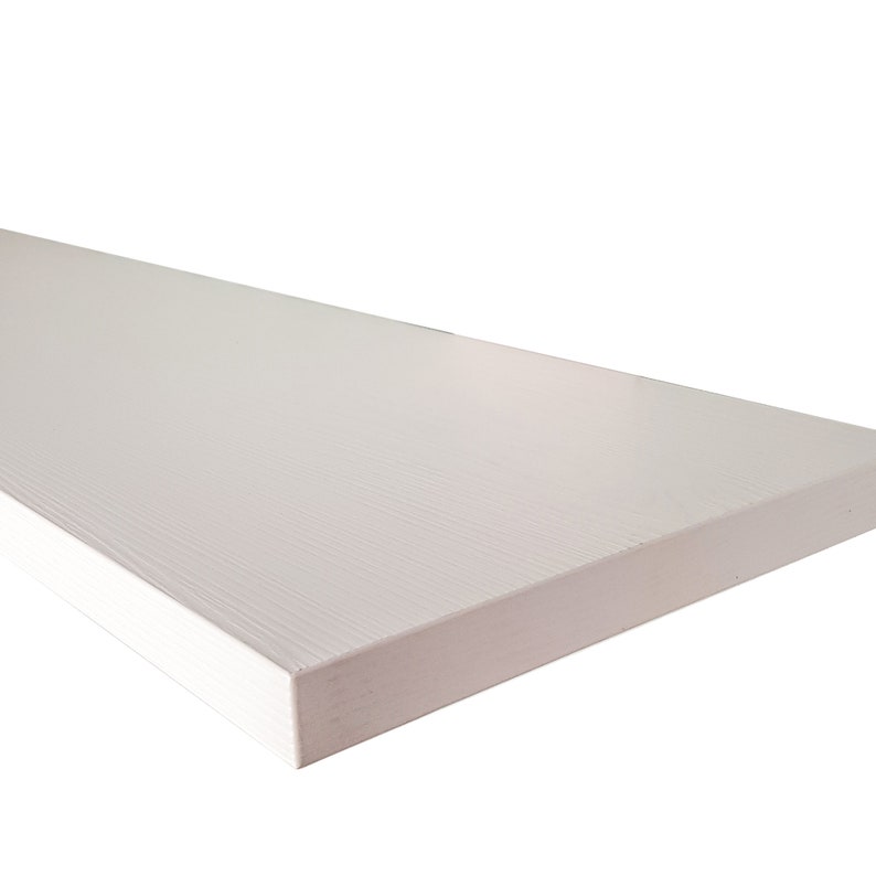 May include: A white floating shelf with a wood grain texture. The shelf is made of a durable material and is perfect for displaying decorative items or storing small items.