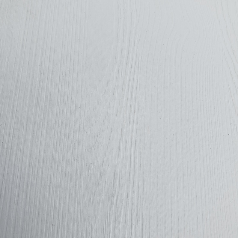 May include: A close-up of a white painted wood surface with a wood grain pattern.